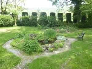 un jardin avec un banc et un étang dans la pelouse dans l'établissement Lyndale House, à Bradwell