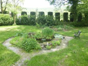 BradwellにあるLyndale Houseの芝生の池とベンチのある庭園