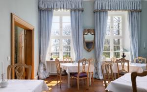 a dining room with a table and two windows at Jagdschloss Kotelow in Kotelow
