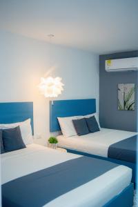 2 camas en un dormitorio con paredes azules y una lámpara de araña en Hotel ADAZ Mediterráneo, en Santa Marta