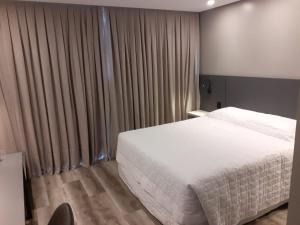a bedroom with a white bed and curtains at Hotel Le Canard Lages in Lages