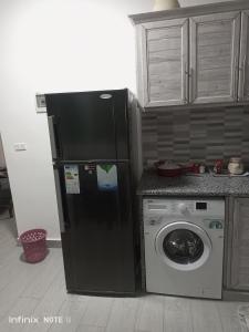 a black refrigerator and a washing machine in a kitchen at Studio Apartment fully furnished super deloux 