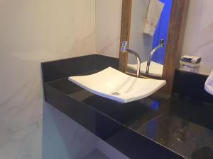 La salle de bains est pourvue d'un lavabo blanc sur un comptoir. dans l'établissement Bahia Flat - Flats na Barra, à Salvador