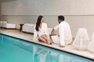 un hombre y una mujer sentados junto a una piscina en Insula Alba Resort & Spa (Adults Only) en Hersonissos