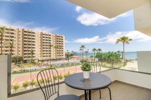 balcón con mesa, sillas y vistas al océano en Ocean House Bloque 3 Planta 1 By IVI Real Estate, en Torremolinos
