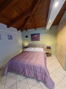 a bedroom with a large bed with a purple bedspread at Semelia's Guest house in Spata