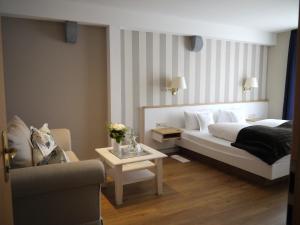 a bedroom with a bed and a couch and a table at Hotel Ratsstuben in Lindau