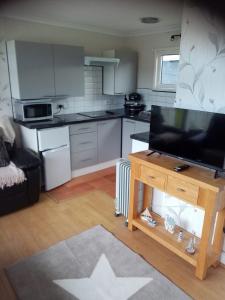 a living room with a kitchen with a flat screen tv at 116 cherry park in Chapel Saint Leonards