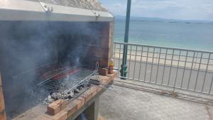 a barbecue grill on a pier next to the ocean at Palmeira in Ribeira