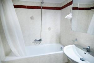 a white bathroom with a tub and a sink at Lili's Apartment in Elefsina