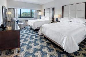 a hotel room with two beds and a television at Sheraton Eatontown Hotel in Eatontown