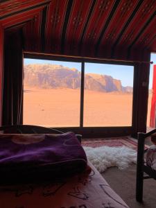 a bedroom with a view of the desert from a window at Bedouin friend camp in Wadi Rum