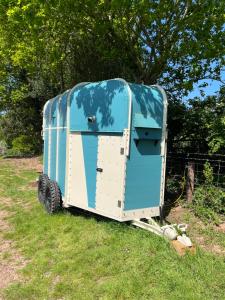 a blue and white trailer sitting in the grass at Bowhayes Farm - Camping and Glamping in Venn Ottery