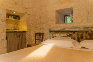 1 dormitorio con 1 cama en una pared de piedra en Trulli Francesca Ciclovia, en Locorotondo
