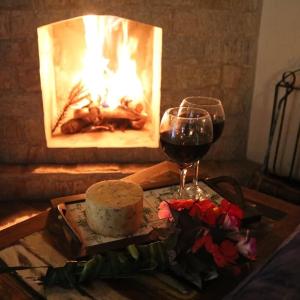 a glass of wine and a cake and a fireplace at Chalés das Orquídeas in Visconde De Maua