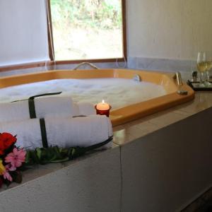 a candle sitting in a bath tub with towels at Chalés das Orquídeas in Visconde De Maua