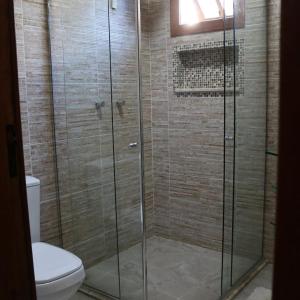 a bathroom with a glass shower with a toilet at Chalés das Orquídeas in Visconde De Maua