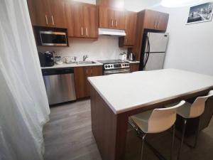 cocina con armarios de madera y encimera blanca en Lovely studio in Longueuil, near Downtown Montreal en Longueuil