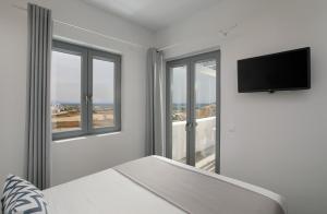 a white room with windows and a flat screen tv at Jardin Mikri Vigla in Mikri Vigla