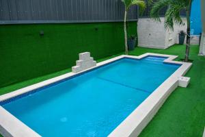 a swimming pool in a yard with green grass at Villa De Cruz - Groovy Suite in Scarborough