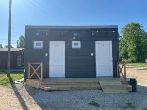 un pequeño edificio negro con dos puertas y un porche en WOMOCAMP Holzhütte 2, en Saulkrasti