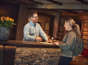 a man and a woman standing at a bar at Brimi Fjellstugu in Fluguhaug