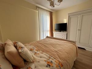 a bedroom with a bed and a flat screen tv at Apartament Rose in Gura Humorului