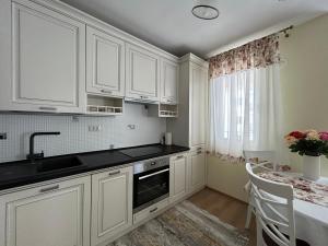 a kitchen with white cabinets and a sink and a table at Apartament Rose in Gura Humorului