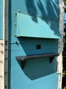 a blue house with a shelf on the side of it at Bowhayes Farm - Camping and Glamping in Venn Ottery