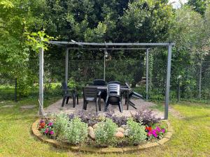 una mesa y sillas bajo un cenador en un jardín en La Cicala - appartamento con giardino privato, en Rivoli Veronese