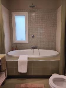 baño con bañera, aseo y ventana en Stella Rossa, en Áno Garoúna