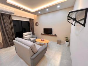 ein Wohnzimmer mit einem Sofa, einem Tisch und einem TV in der Unterkunft Mandarin Fish Homestay in Magong