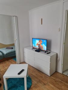 uma sala de estar com uma televisão de ecrã plano numa cómoda em Nébel Vendégház em Komárom