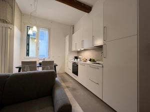 a kitchen with white cabinets and a couch in a room at Cesare Battisti Home in Bologna