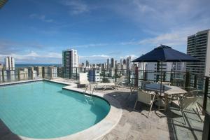 a swimming pool on top of a building with an umbrella at Flat Quarto e Sala, 400 metros da Praia de Boa Viagem, com Piscina, Wi-Fi 220Mbps in Recife