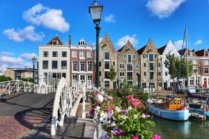 a bridge over a river with flowers and buildings at Elysian Yellow Suite in Middelburg