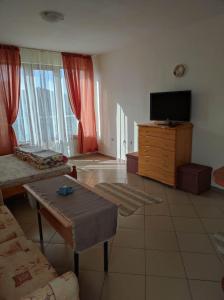 un salon avec une télévision, un canapé et une table dans l'établissement Студио Слънчево утро, à Bourgas