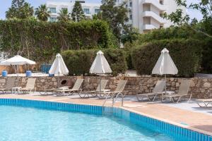 a swimming pool with lounge chairs and umbrellas at Flora Hotel Apartments in Protaras