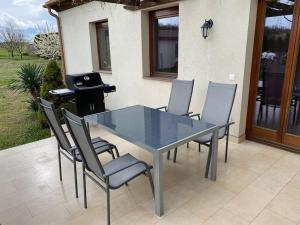 a glass table with chairs and a grill on a patio at Szent Kard Vendégház in Sóly