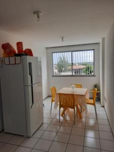 uma cozinha com um frigorífico e uma mesa com cadeiras em Apartamento por temporada em Fortaleza