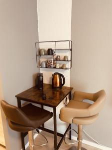 a table with two chairs and a tea kettle on it at New Modern Apartment City Center 03 in Mainz