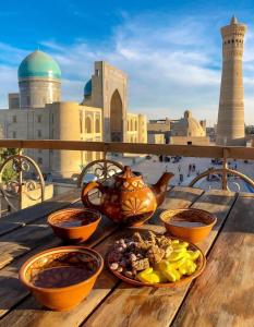 a table with bowls of food on a table with a view at Jahangir Boutique Bukhara in Bukhara