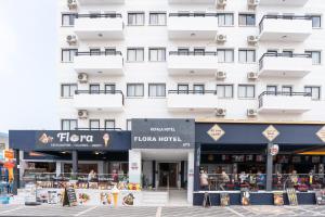 a large white building with balconies and shops at Flora Hotel Apartments in Protaras