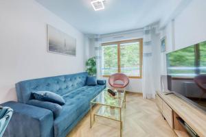 een woonkamer met een blauwe bank en een tafel bij Amazing apartment in a park overlooking Paris in Meudon