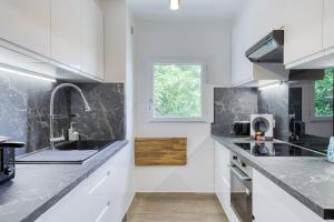 een keuken met witte kasten en zwarte aanrechtbladen bij Amazing apartment in a park overlooking Paris in Meudon