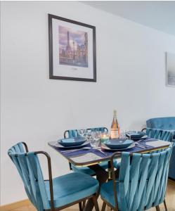 een eettafel met blauwe stoelen en een fles wijn bij Amazing apartment in a park overlooking Paris in Meudon