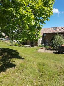 a house with a yard with a tree and a grass field at chambre à la campagne Saint André de Chalencon in Saint-André-de-Chalençon