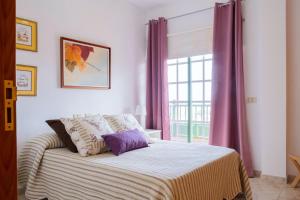1 dormitorio con 1 cama con cortinas moradas y ventana en LIVE GUANCHES DE CANDELARIA en Candelaria