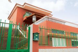 a red building with a green fence in front of it at Live Guanches de Candelaria in Candelaria