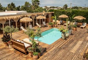 a wooden deck with a swimming pool with chairs and umbrellas at Can Aisha - Adults Only in Es Pujols